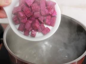 汤锅洗净，倒入4碗食用水，盖上盖子煮沸，把切好的紫薯小方块，倒入锅里。这是4个人的早餐用量，2个紫薯、4包燕麦片，这个配料刚刚好，一家四口一人一碗。