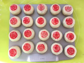 烤箱预热180度，用印章沾上适量的红色色素，在月饼表层压出花型