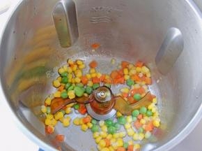 杯体中安装搅拌勾，设置温度100度，时间1分钟，放入一勺食用油，将食用油烧热，油热以后放入什锦杂蔬粒，L档翻炒1分钟。