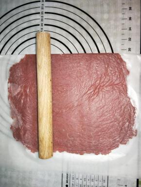 底下铺一张油纸，放上肉馅，上面覆盖一张保鲜膜，擀薄