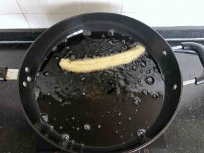 12、拿起一块面剂，捏紧两头，稍微抻长放入油锅，炸至金黄色捞出。