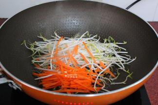 锅中少许油，倒入胡萝卜丝、豆芽；先放豆芽和胡萝卜，能让河粉暂时不接触到锅底，这样河粉就不会粘锅。