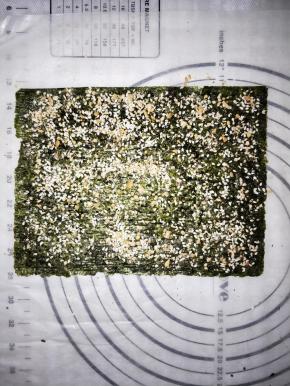 取一样海苔，选择粗的一面刷一层酱汁，撒上薄薄一层花生芝麻