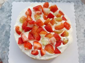 把蛋糕胚从中间切成两片，取一片放在转台上抹上一层奶油，铺一层草莓碎。