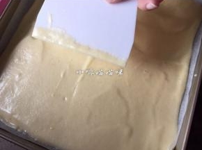 用刮板将面糊表面刮平，将烤盘提起至距离桌面5厘米高度敲摔出起泡