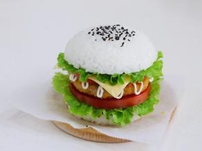 接着放上一片西红柿片、芝士片、生菜，最后把涂抹番茄酱的米饭团盖上，撒少许黑芝麻装饰。