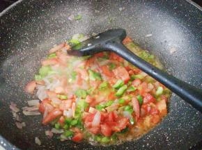 把青椒丁倒入炒制下，接着倒入番茄丁炒制汁水