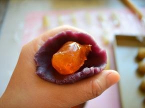 把每个紫薯馅按扁，把蛋黄放中间，利用虎口，往上捏，最后收口，备用