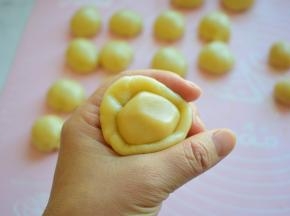 取一个油皮，按扁，再把油酥放中间，用虎口往上捏，包紧收口，全部包好，放在案板上，盖保鲜膜静置15分钟