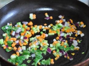 锅里倒入油，将胡萝卜丁、洋葱丁、切碎的菜心放入锅中。