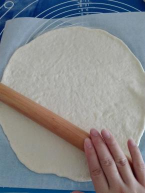 用擀面棍稍为擀平。
转移到油纸上铺平，按着一边油纸，用擀面棍尽量往外擀成均匀的薄饼。