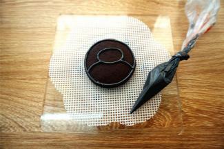 用黑色浓稠糖霜给每一块饼干绘大白图案及外圆轮廓。