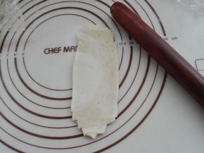 将卷过两次的面卷，再次用擀面杖将其擀成长条，如图所示。