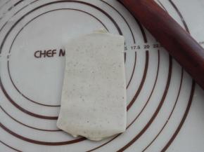 将折叠三折后的面团，对折面朝下放置，同样用擀面杖将其最后再擀长一下，成一个小长方形即可，如图所示。