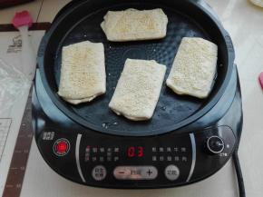 电饼铛预热好后，将醒发好的面胚表面刷层水，沾上芝麻，稍微按压一下，放入电饼铛中，将其烙制作两面金黄色即可。