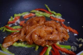 再加入腌制好的鸡肉，大火翻炒至变白