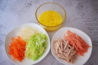 鸡蛋打散备用，将火腿肠、肉卷、胡萝卜、白萝卜、包菜全部切丝备用