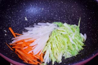 原锅倒入适量的食用油烧热，再放入胡萝卜、白萝卜、包菜翻炒至变软
