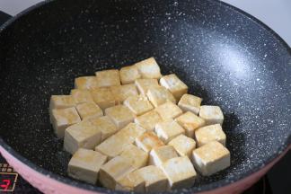 锅热后倒入适量玉米胚芽油，放入豆腐块煎至两面金黄，期间记得翻面;