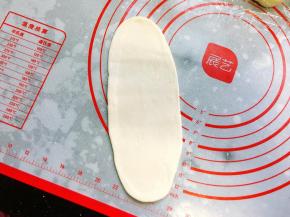 收口朝上，用手压扁后再用擀面棍擀开成长椭圆形，擀的时候不要太用力，否则容易破皮。