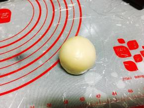 按扁后用擀面棍擀成大面片，取1粒豆沙馅放在面片中间，然后包起来，收紧口。