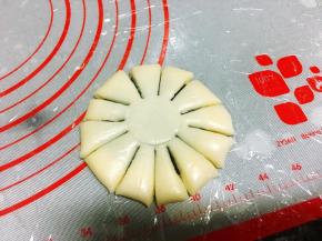 收口向下，压扁成大饼状，一定要扁一些，太厚不好看，用一个矿泉水瓶盖在中间轻轻压出一个圆印，接着用小刀平均分割成12份，可以先1分为4，然后在每1份里割上均等大小的两刀。