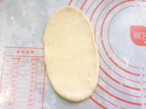 将松弛好的面团擀成长舌状，用手拍掉两边的气泡，翻面后从上往下卷成橄榄形，捏紧收口。