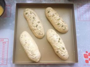 在发酵好的面包胚表面刷上一层薄薄的蛋液，然后撒上坚果仁。