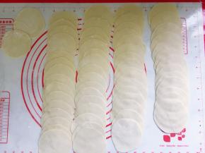 将小剂子一一沾粉按扁，用擀面棍擀成中间厚两边薄的圆片。