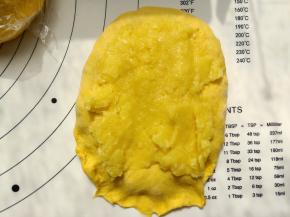 取一份面团擀成牛舌形，取六分之一的奶黄馅铺在擀好的面团上，然后卷起来。