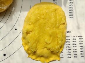 取一份面团擀成牛舌形，取六分之一的奶黄馅铺在擀好的面团上，然后卷起来。