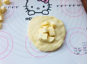 5、松弛好后的面团，按扁，将耐高温奶酪丁包裹在里面，收口一定要捏紧。