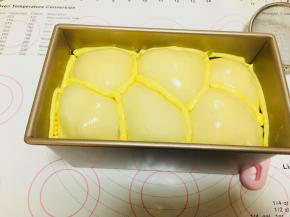 8、将软化的黄油装入裱花袋中，剪一个小口，将它挤到吐司表面的凹陷处。