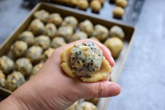 取出一个月饼面团，按扁，把馅放中间，包好，倒扣