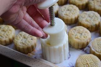 把包好的月饼表面抹一层薄薄的淀粉，用月饼模具压出花形