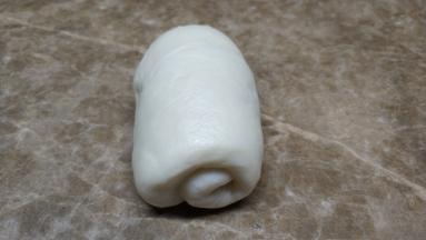 将鬆弛好的麵糰分别擀成长椭圆形，两边向中间叠起擀平，由上至下卷起来