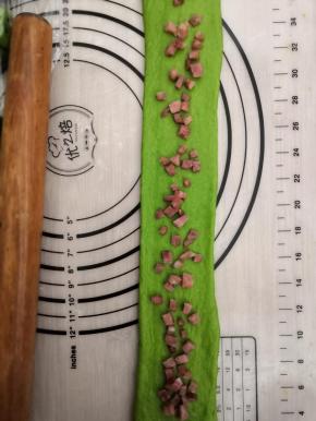 取其中一个擀成牛舌状，长度在45厘米左右，均匀的撒上火腿丁