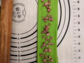 取其中一个擀成牛舌状，长度在45厘米左右，均匀的撒上火腿丁