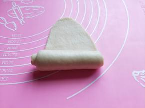 取一块小面团，用擀面杖擀长舌状。由上到下卷起来。