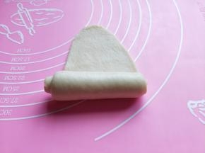 取一块小面团,用擀面杖擀长舌状。由上到下卷起来。