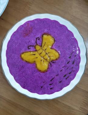 拿个蝴蝶模具放到碟子中间，先在外面倒入火龙果奶昔，然后蝴蝶部分倒入芒果。