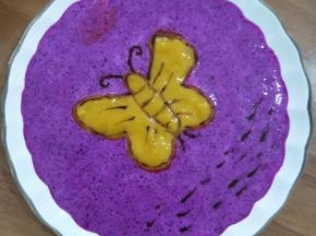 拿个蝴蝶模具放到碟子中间，先在外面倒入火龙果奶昔，然后蝴蝶部分倒入芒果。