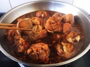 将电压力锅压制好的猪手倒入另外一款炒锅里，捞出调料包弃之。