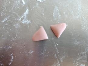 1.5克红色面团搓成两头尖中间粗的梭状，压扁，分成两份，做耳朵
