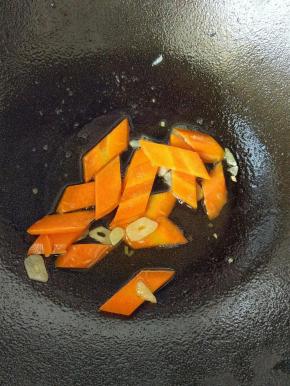 锅里再放点油，放蒜片炒出味道，然后放胡萝卜片，翻炒会。