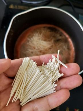 把西红柿汁倒入奶锅，再加适量水烧开。然后拿出面条，掰成小段，放入奶锅里，转小火煮。