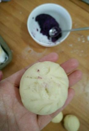 取个大的剂子，放适量紫薯陷，包好并搓成椭圆形。(稍微搓一下，比圆形长一点就好。)然后摆在烤盘里，再取个小剂子搓圆，抹点水，沾到椭圆形包子上方。