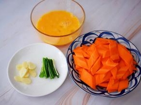 鸡蛋打散备用，胡萝卜去皮洗净先斜段再竖着切片，蒜切片，葱切寸段