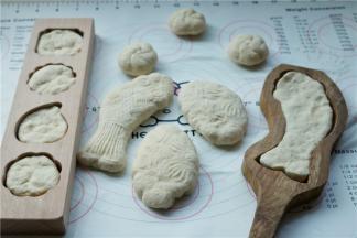 取适量面团，放入模子，使劲按压一下，使形状清晰。模子翻过来使劲磕一下，巧果胚子就出来了。