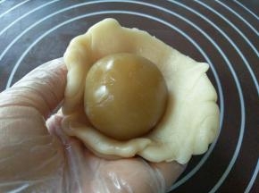 擀好的面皮包进一个莲蓉，也是用收虎口的方包包好